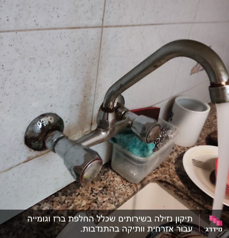 ברז מטבח עם מים זורמים בכיור מלא כלים